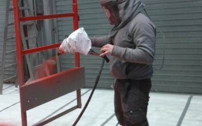 Lackierer lackiert ein Gestell mit dem elektrostatischen Lackierverfahren