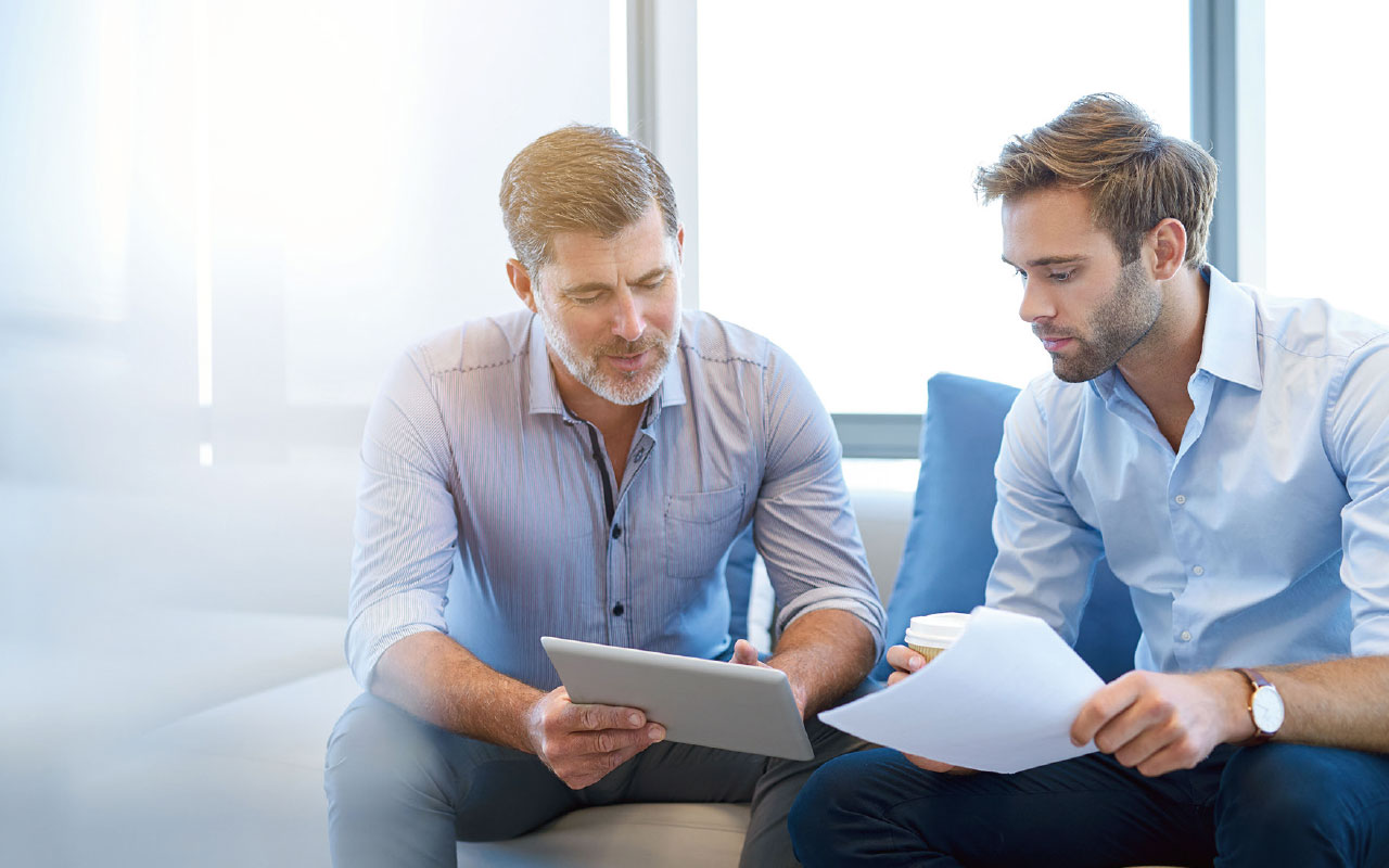 zwei Personen mit Unterlagen in der Hand besprechen sich